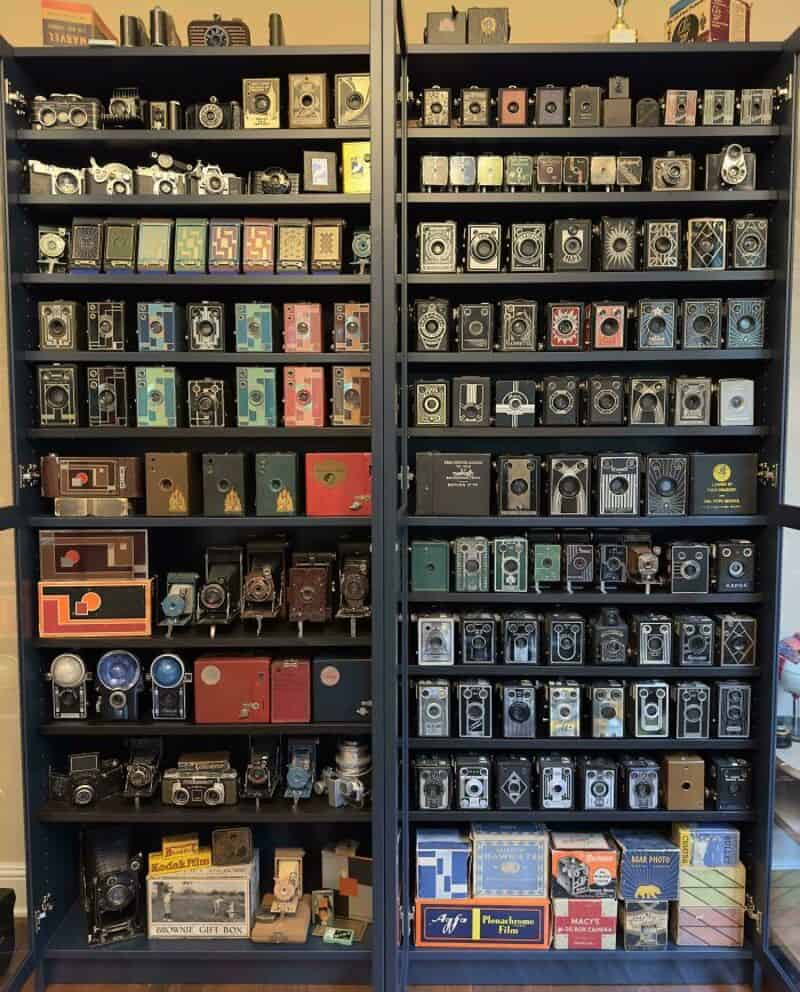 Shelf filled with vintage cameras and camera boxes in a store.