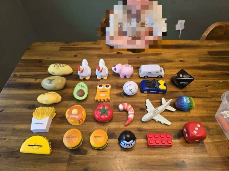 Collection of small toys and objects on a wooden table, including bunnies, a plane, and a red die.