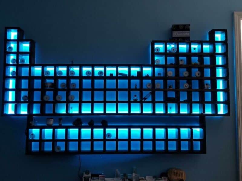 Blue illuminated storage shelves with various items against a blue wall.
