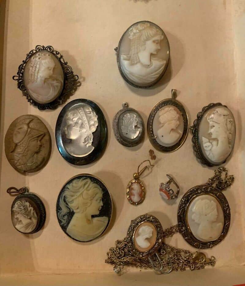 Collection of vintage cameo jewelry including brooches, pendants, and chains.