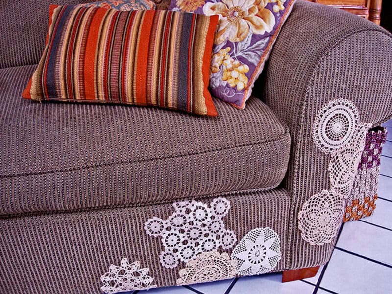 Close-up of a sofa with crochet doilies and a striped pillow.