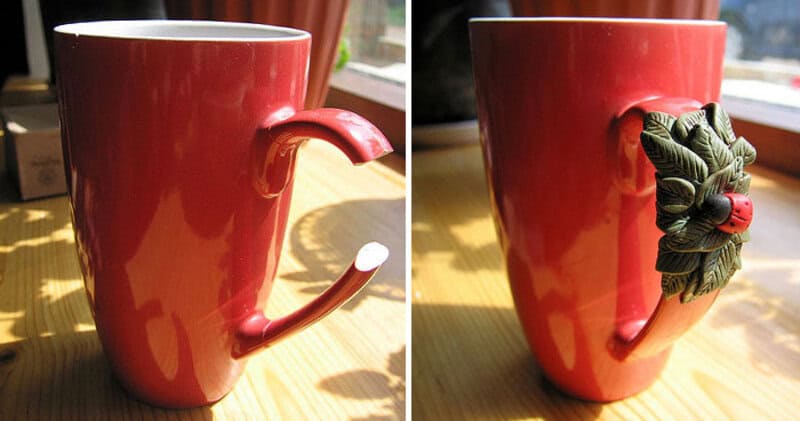 Red mug with a bent handle resembling a hook, decorated with a green leaf and red berry ornament.