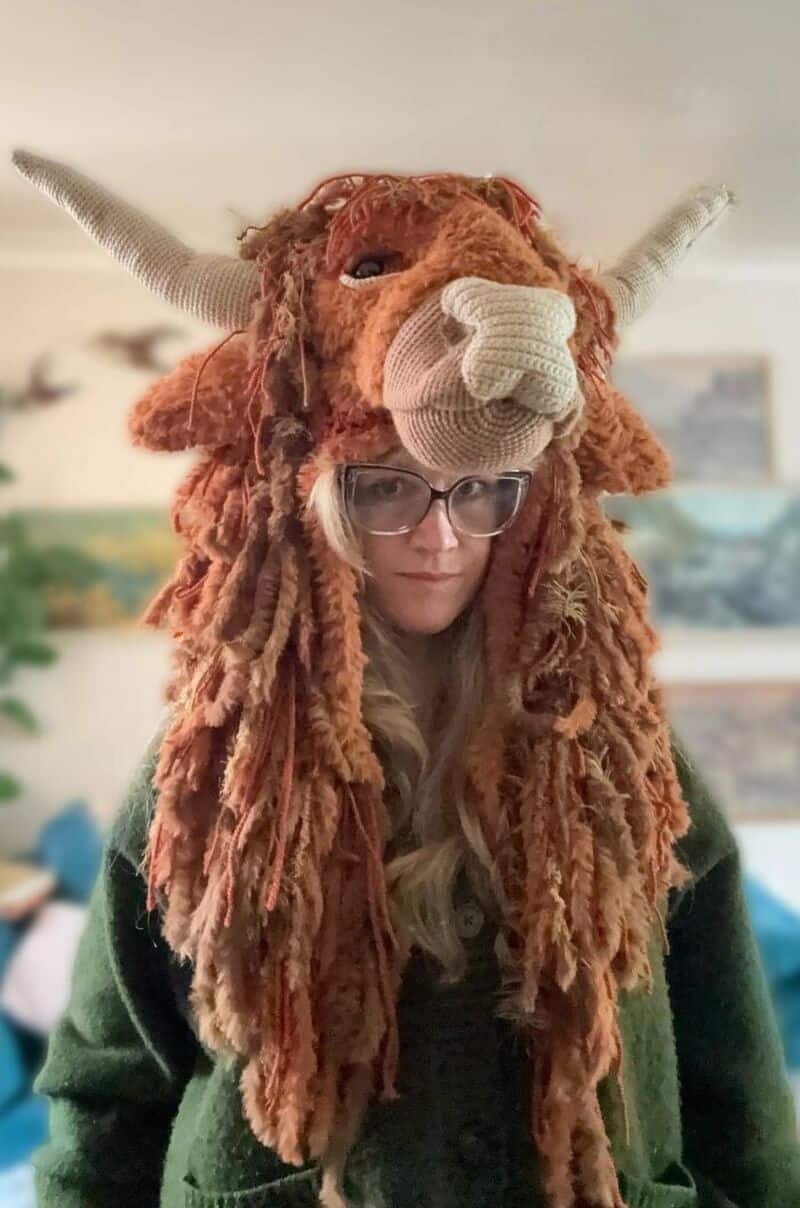 Person wearing a lion hat with yarn mane, horns, and face details.