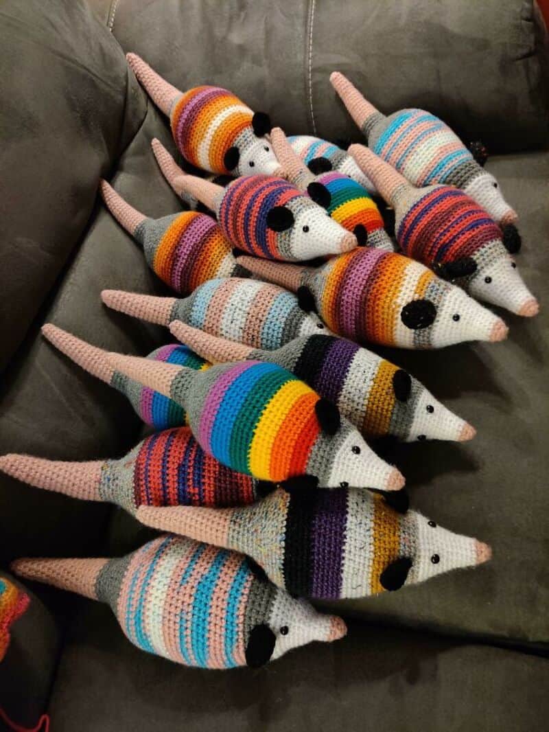 Colorful crocheted mice with striped patterns on a dark sofa.