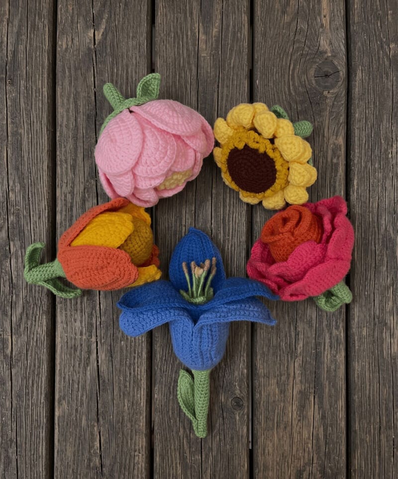 Colorful crochet flowers arranged in a circle on wooden background.