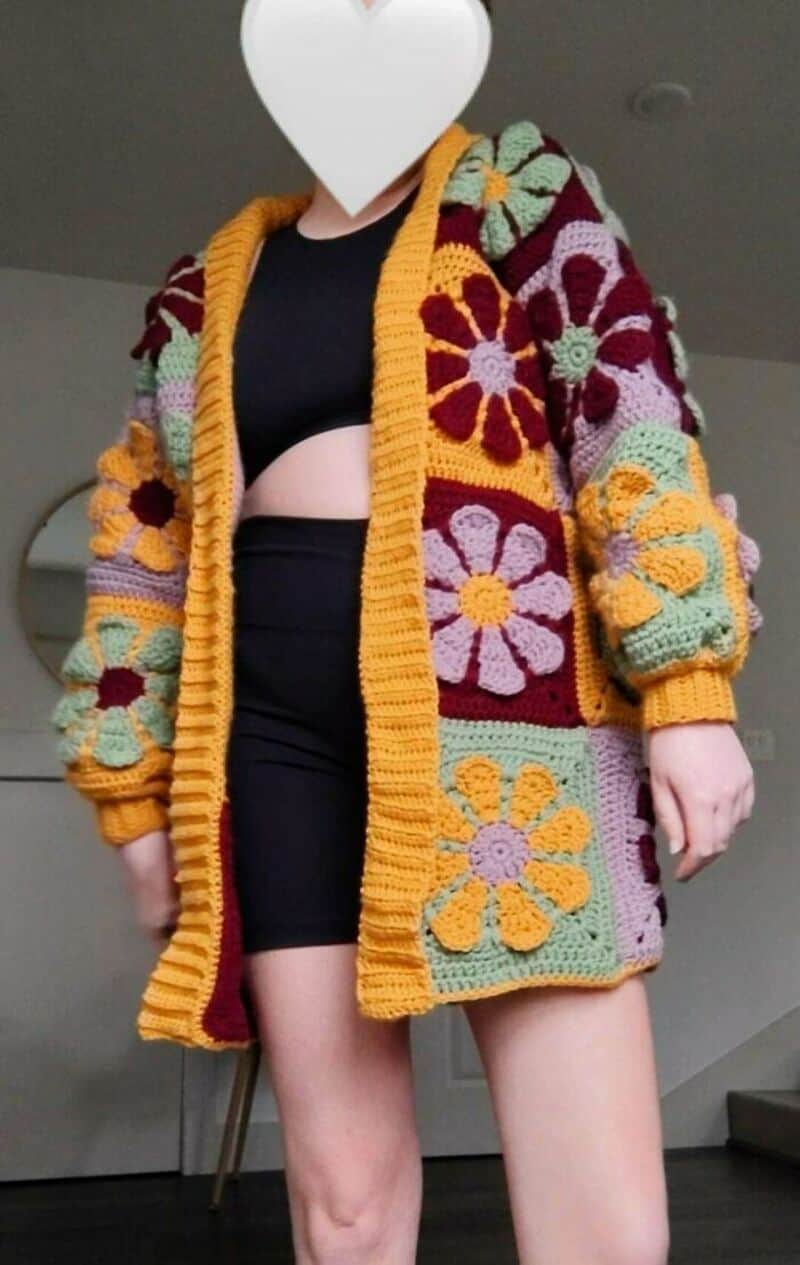 Colorful crochet cardigan with large flower patterns and yellow trim.