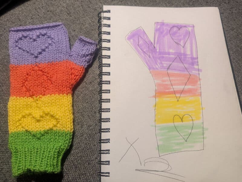 Colorful rainbow crochet glove with purple heart and a drawing of the word 'LOVE' on paper.