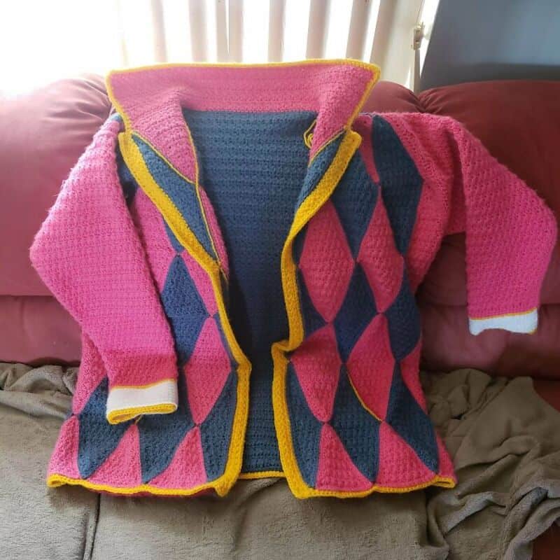 Colorful crocheted jacket with pink, blue, and yellow patterns on a couch.