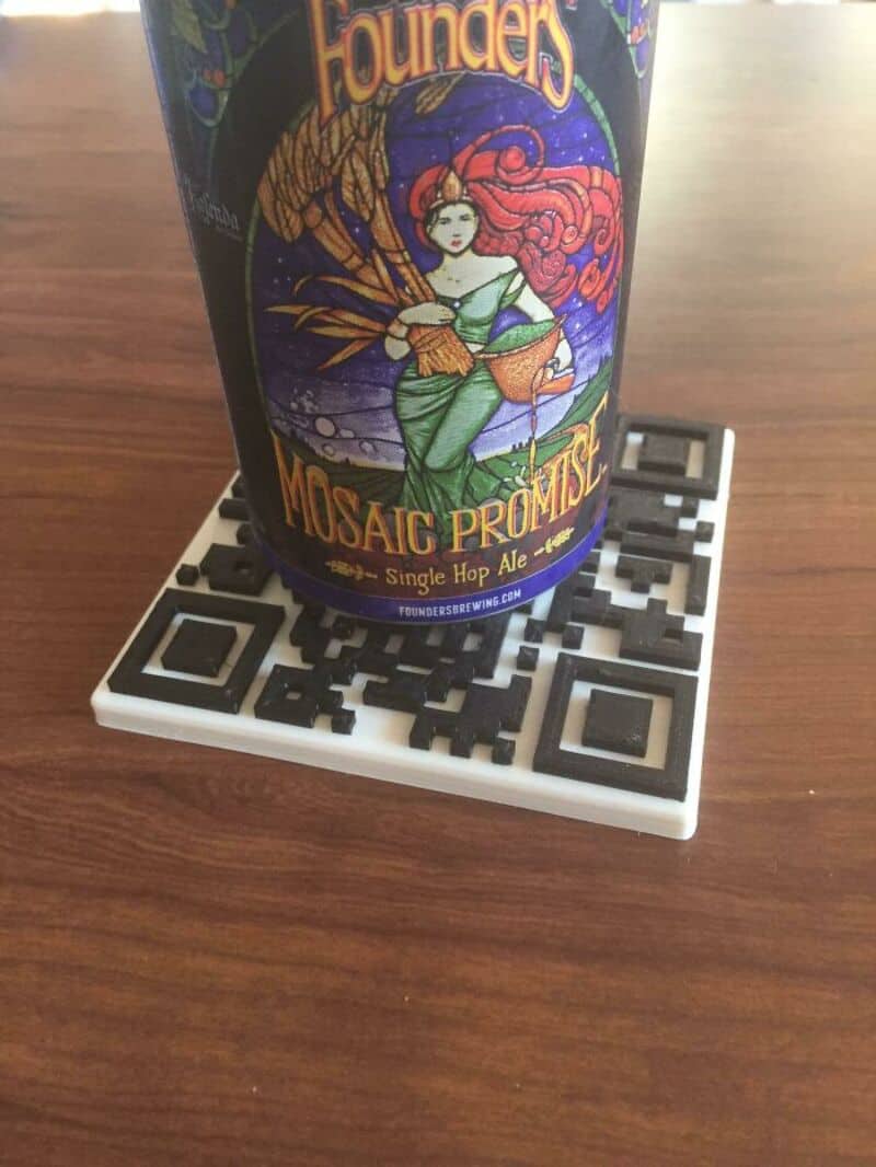 Beer can with colorful label on a 3D-printed QR code coaster.
