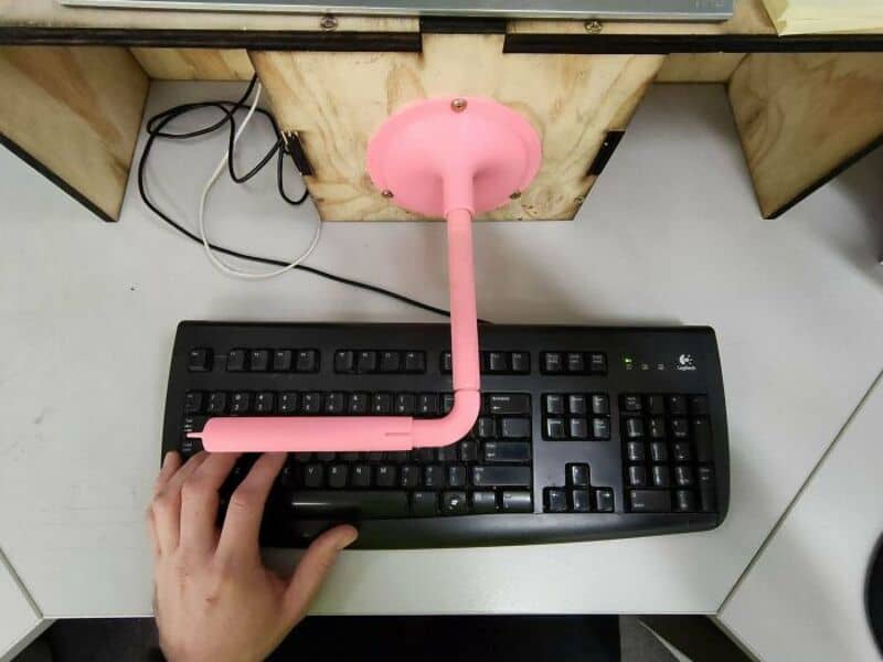 Pink 3D-printed pipe with a round top on a computer keyboard.