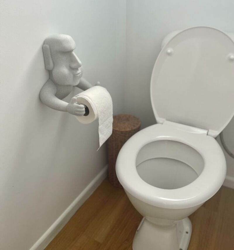 Toilet paper holder with a 3D-printed figure of a person reading a book.