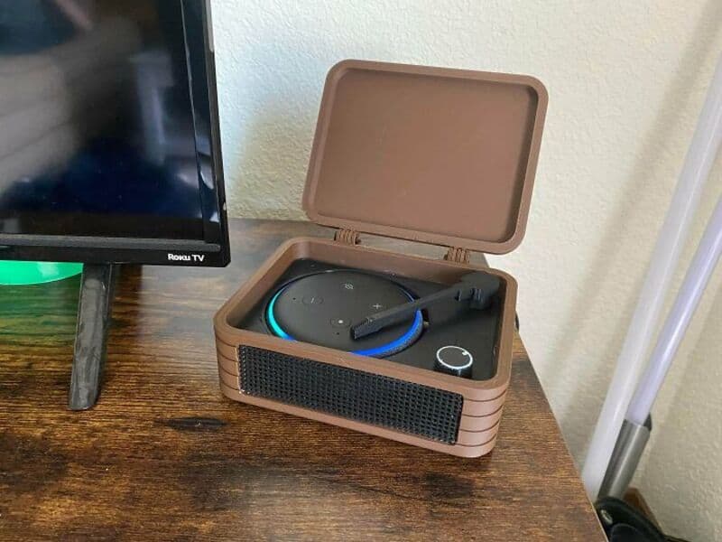 Portable Bluetooth speaker in a brown case on a wooden surface.