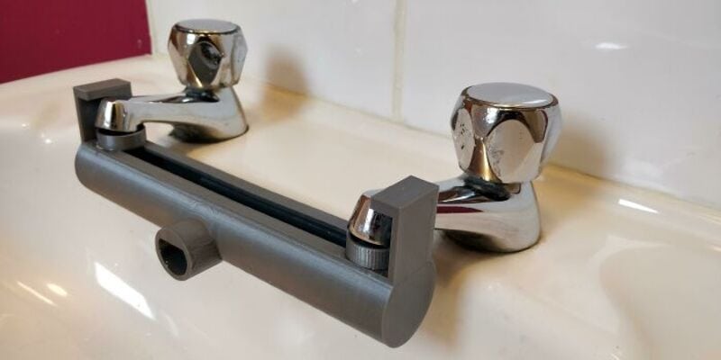 Close-up of a silver faucet with a black bar in a bathroom sink.