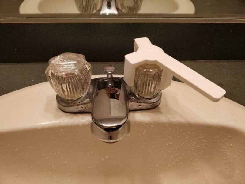 Faucet with a white 3D-printed handle on a bathroom sink.