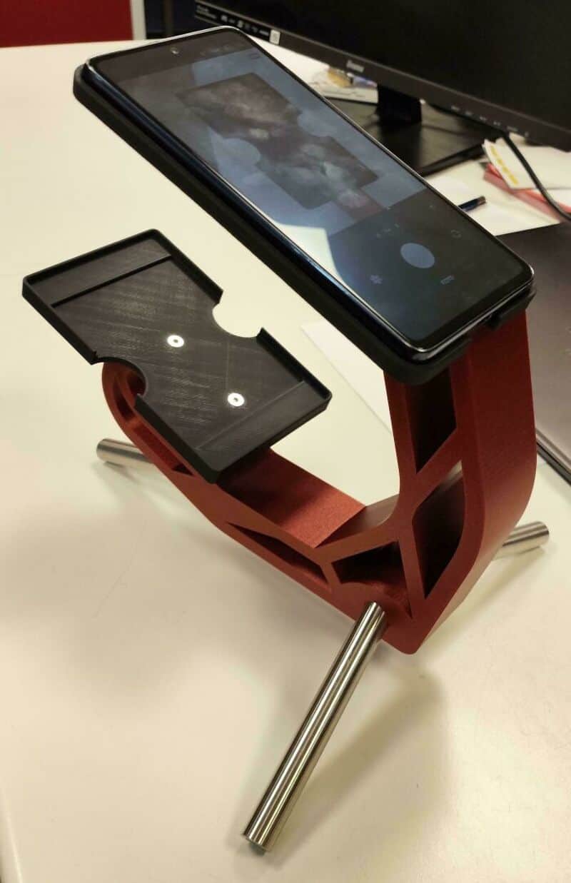 Smartphone on a custom 3D-printed stand with a black base and red support structure.