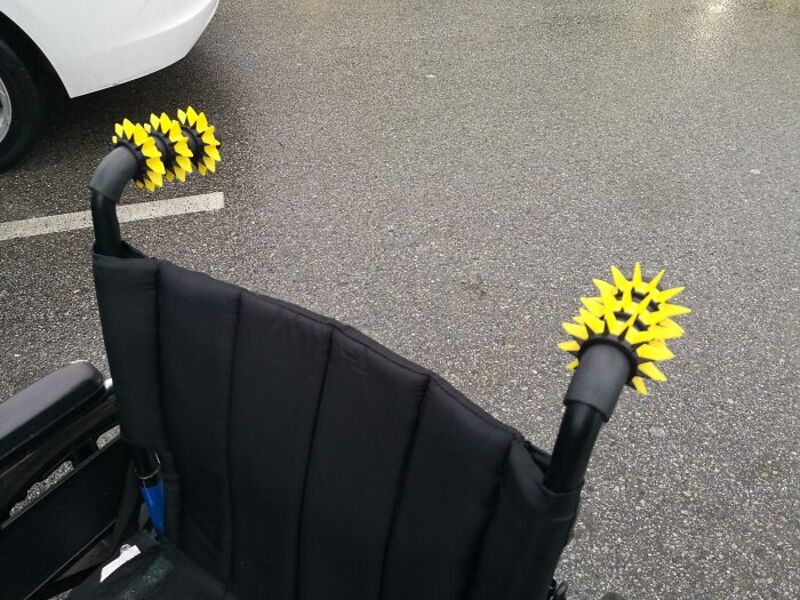 Yellow spiked attachments on black handles attached to a black stroller.