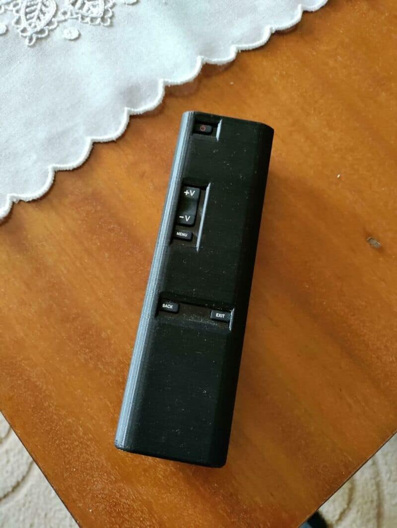 Remote control with volume and menu buttons on a wooden table.