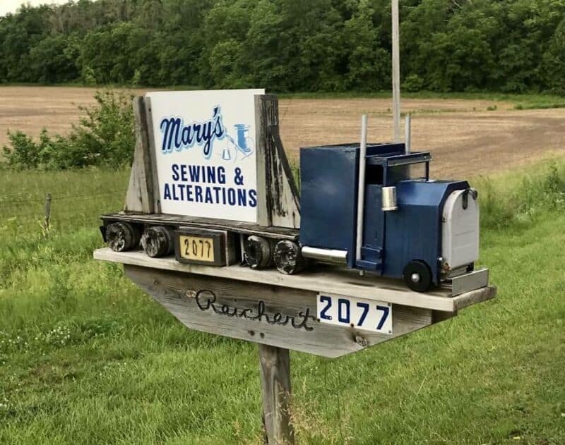 Miniature train mailbox with sign for Mary's Sewing & Alterations, located in a rural area.