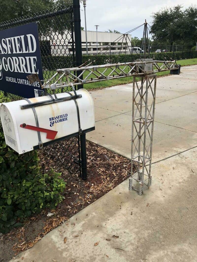 Damaged metal structure near mailbox and fence, with construction sign in background.