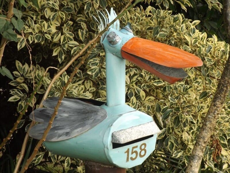 Decorative mailbox shaped like a bird with a blue body, orange beak, and gray wings, numbered 158.