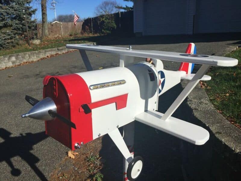 Red and white mailbox shaped like a small airplane with a propeller.