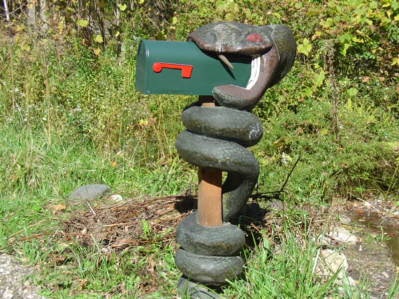 Snake-shaped mailbox sculpture with a green mailbox in its mouth.