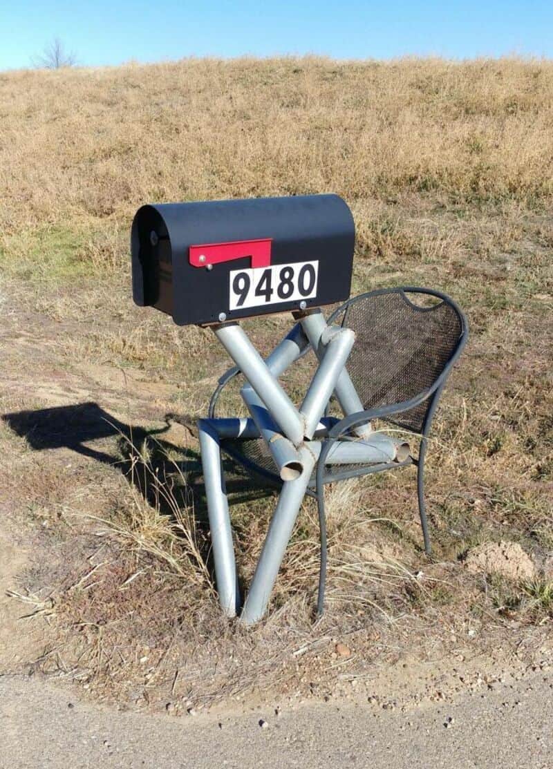 Mailbox with the number 9480 on a metal stand in a field.