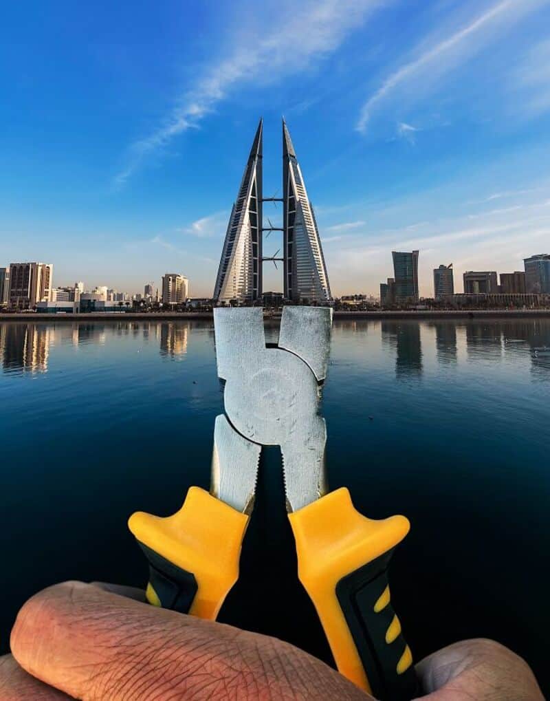 Person holding a yellow and black glove with a city skyline and water in the background.