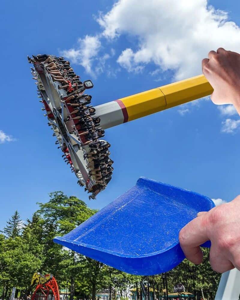 Person holding a blue scoop and a spinning amusement park ride in the sky.