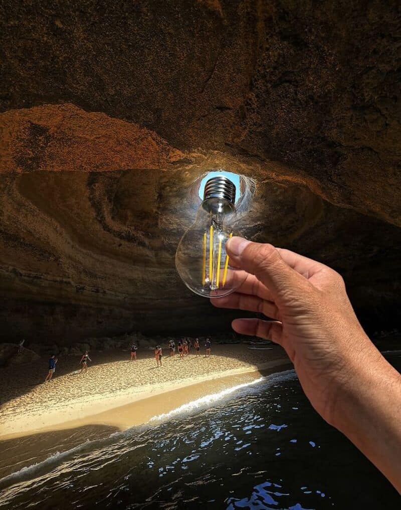 Person holding a light bulb under a rock overhang at the beach.