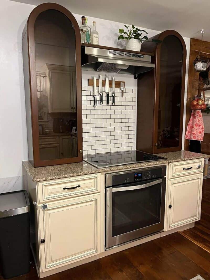 Kitchen with wooden cabinets, white brick backsplash, and oven.