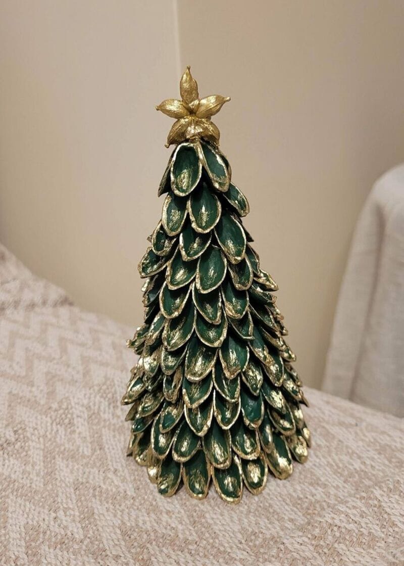 Decorative Christmas tree made of green and gold shells with a gold star on top.