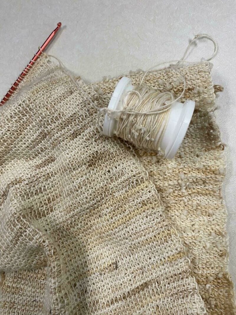 Yarn, crochet hook, and woven fabric for upcycling crafts.
