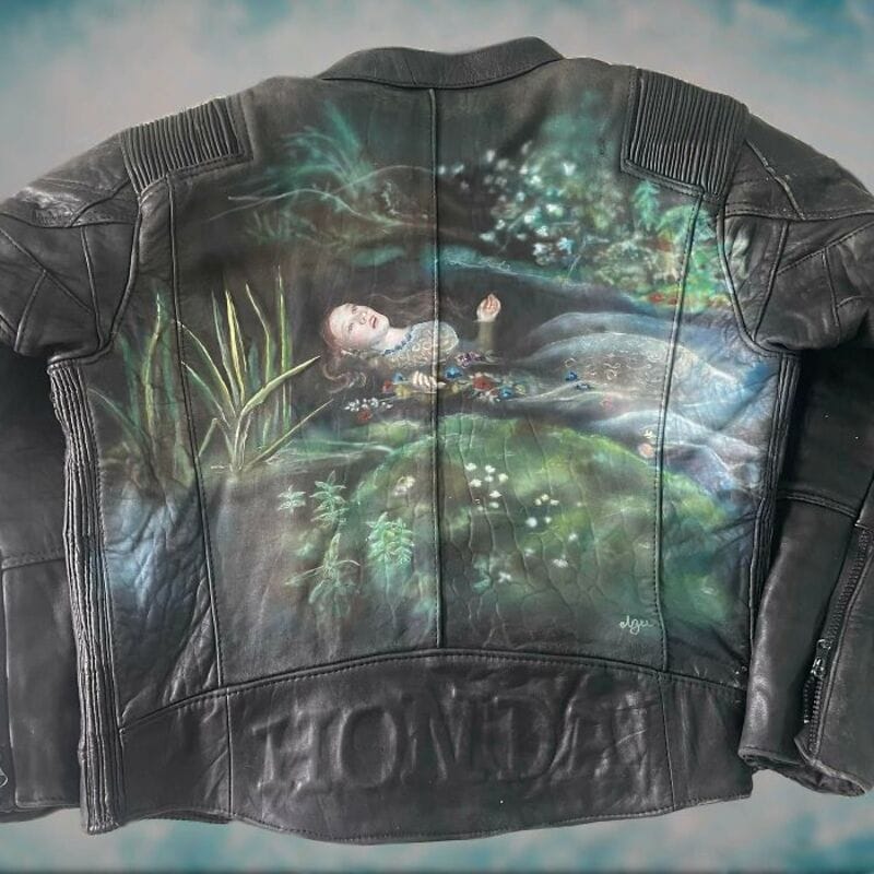 Leather jacket with a painted scene of a girl lying in a pond surrounded by nature.