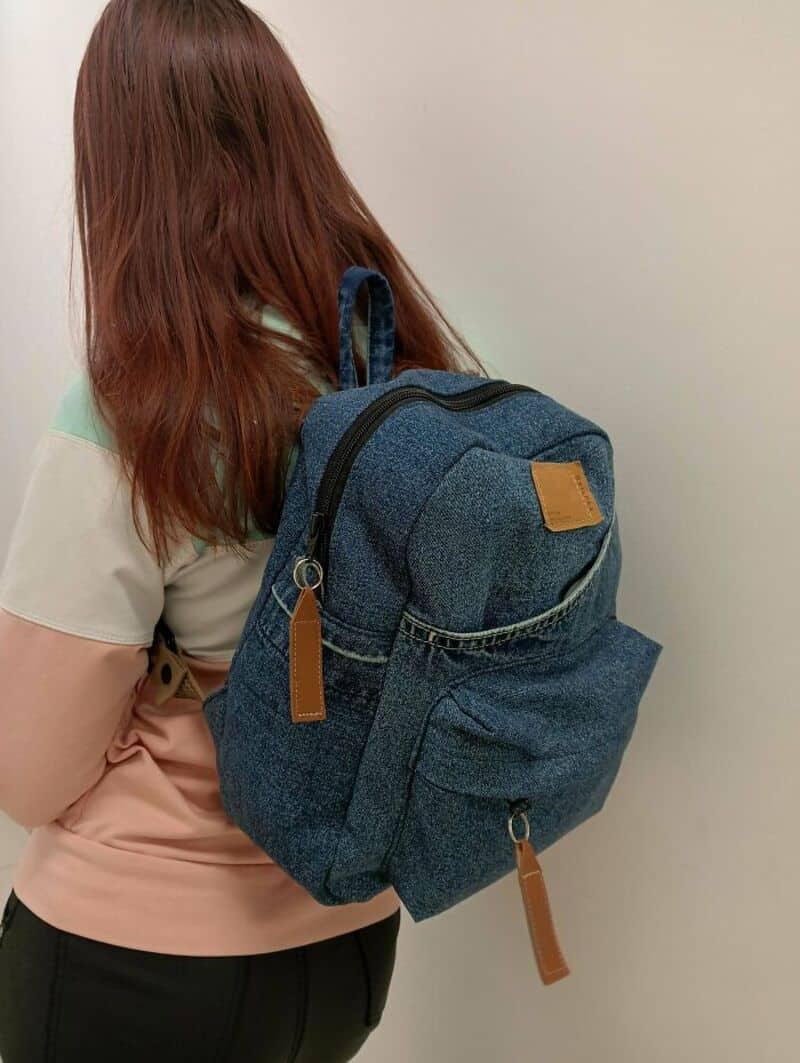 Back view of a woman with a blue backpack, wearing a pastel-colored top.