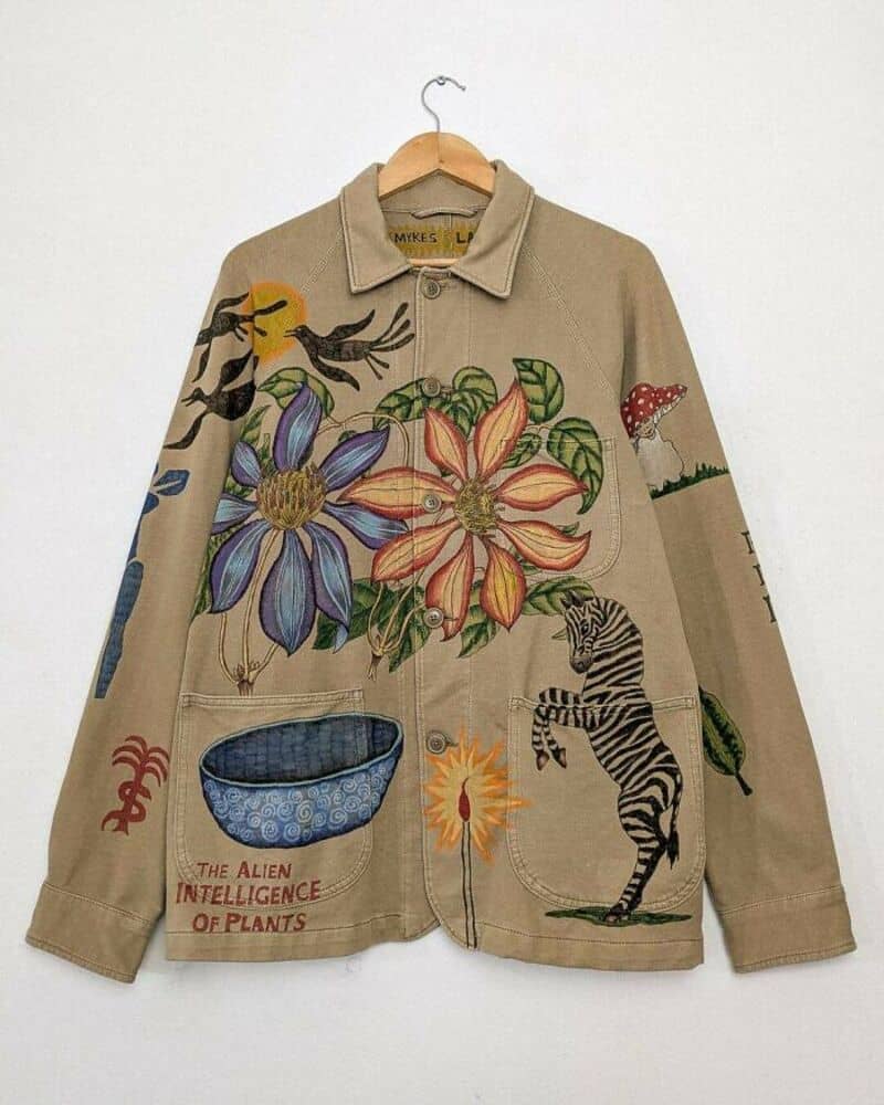 Upcycled beige jacket with colorful painted floral and animal designs.