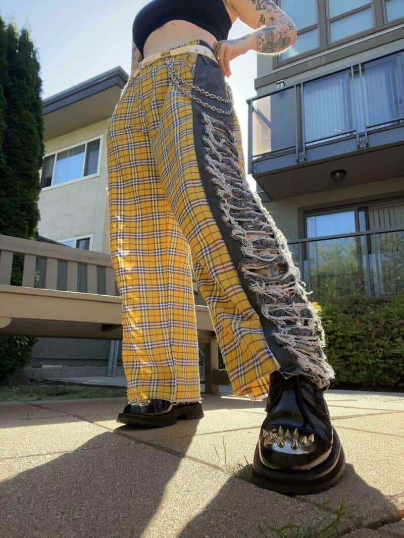 Person wearing yellow plaid pants and black platform shoes, standing outside.
