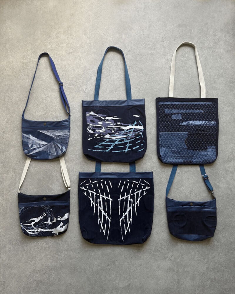 Collection of six upcycled bags with blue and white designs on a gray background.