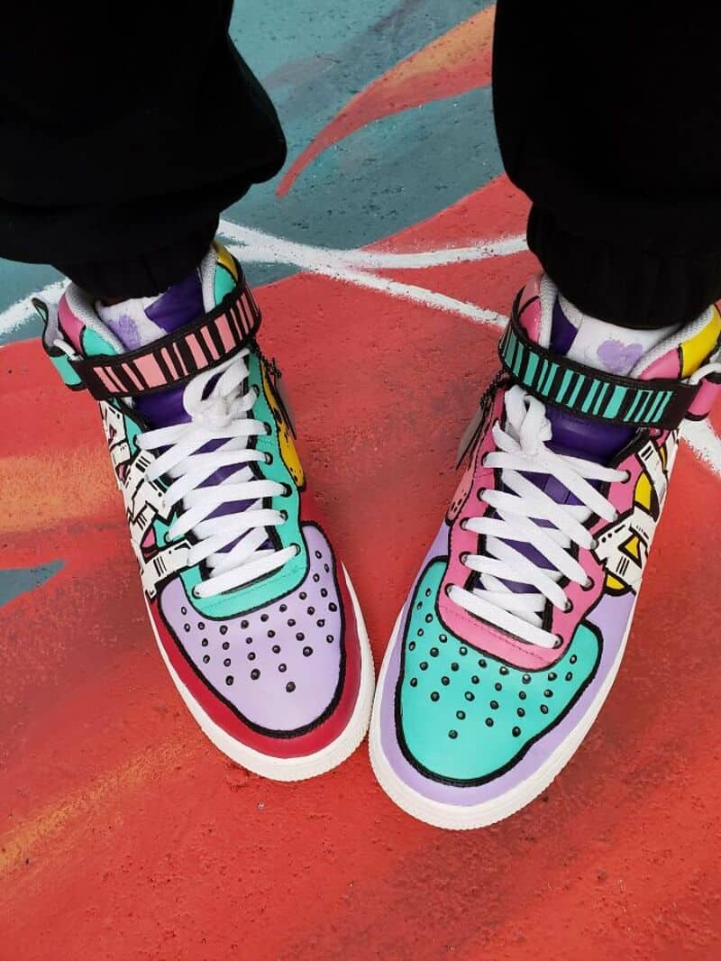 Colorful sneakers with a rainbow design on a red and blue court.