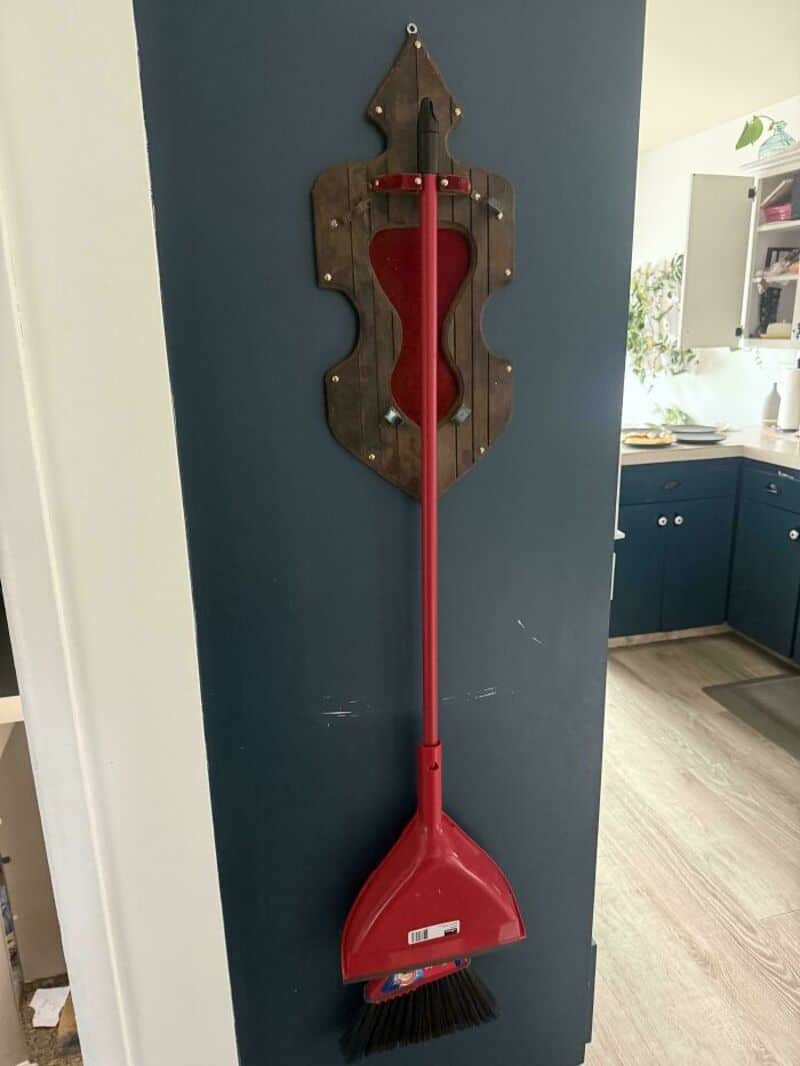 Upcycled broom and dustpan wall decor with a heart-shaped cutout.
