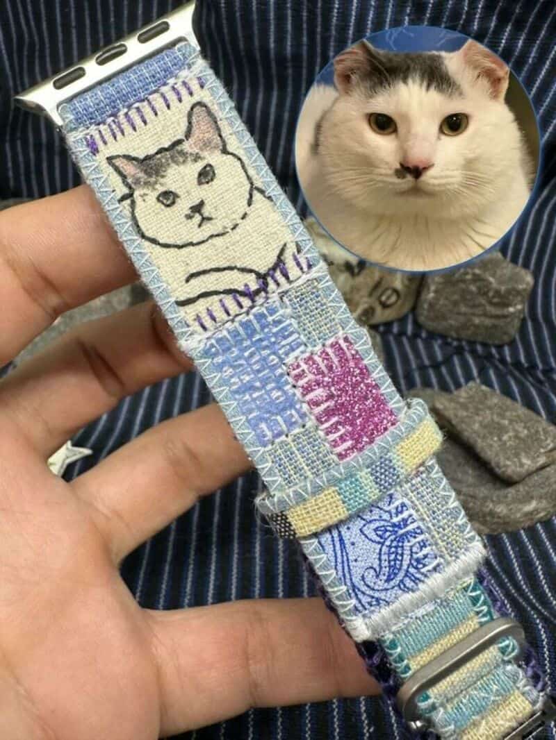 Upcycled fabric cat-themed watch band with embroidered cat face and blue patterns.