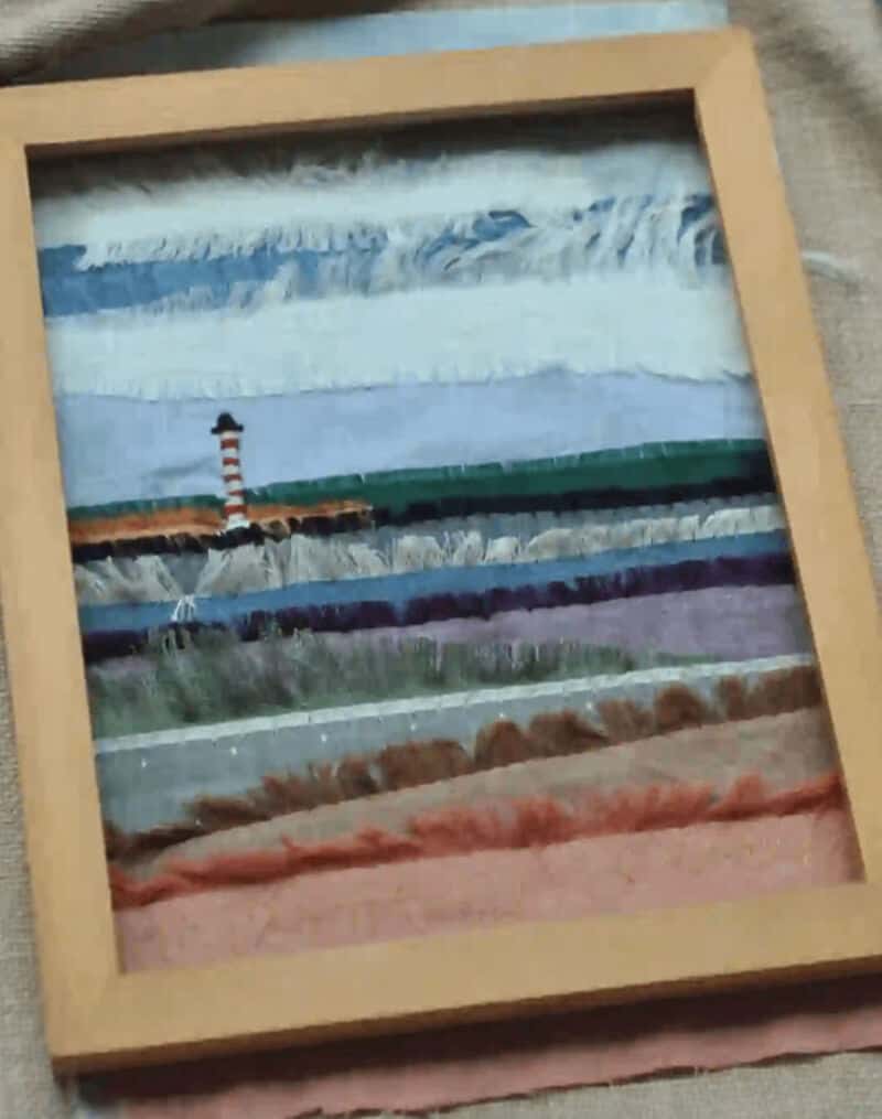 Colorful fabric strips arranged in a frame with a lighthouse in the background.