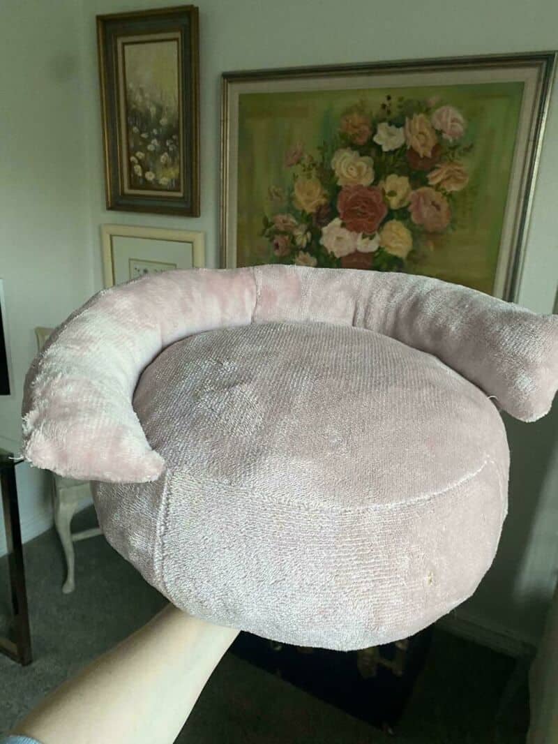 A plush, light pink, crescent-shaped chair with a rounded seat and backrest.
