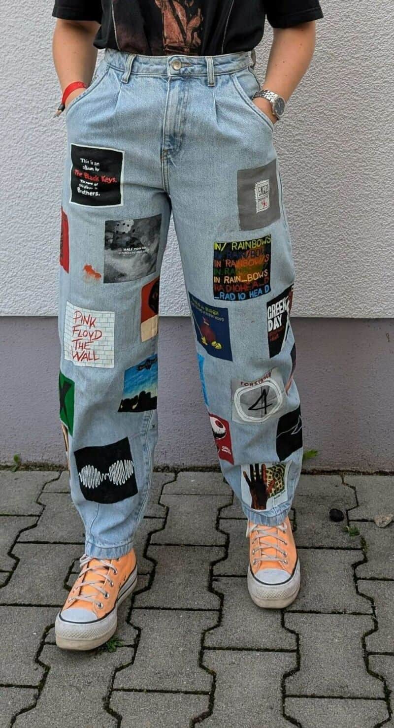 Person wearing light blue upcycled jeans with various patches and designs.