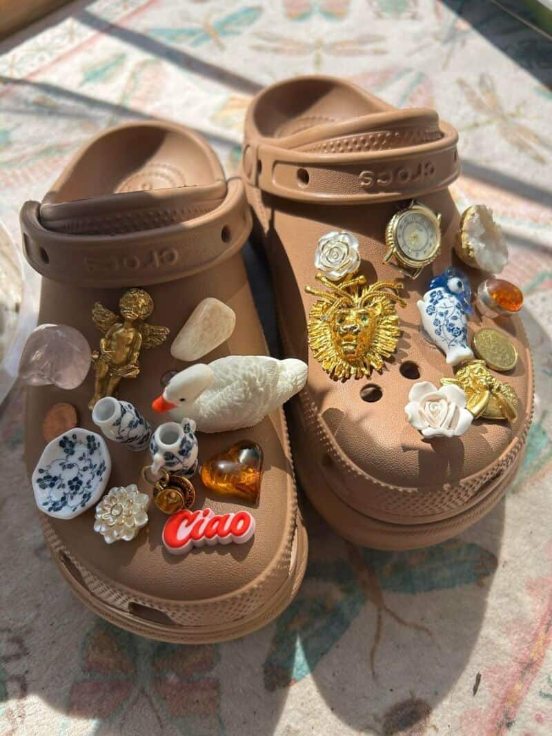 Pink Crocs filled with various jewelry and small decorative items, outdoors.