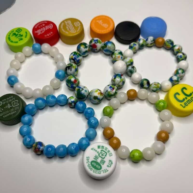 Colorful beaded bracelets with bottle caps on a white background.