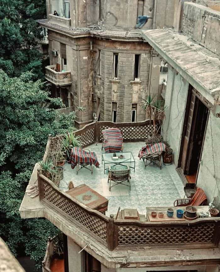 Balcony with outdoor furniture and potted plants on an old building.