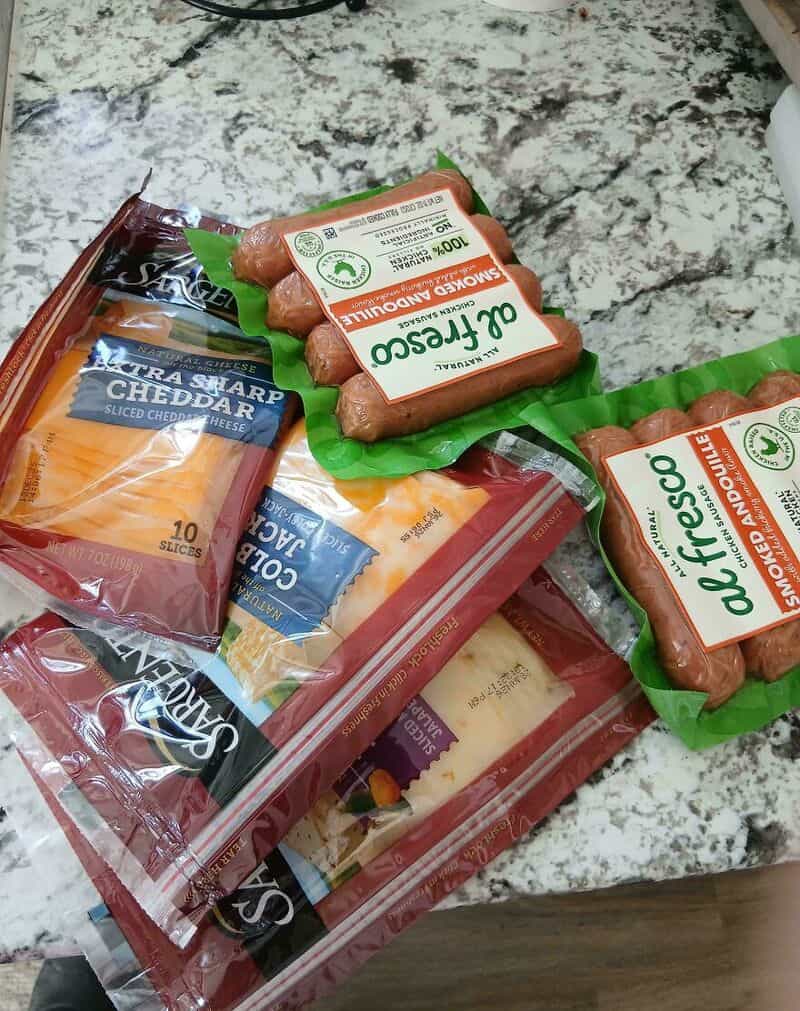 Assorted sliced cheese and sausage on a kitchen counter.