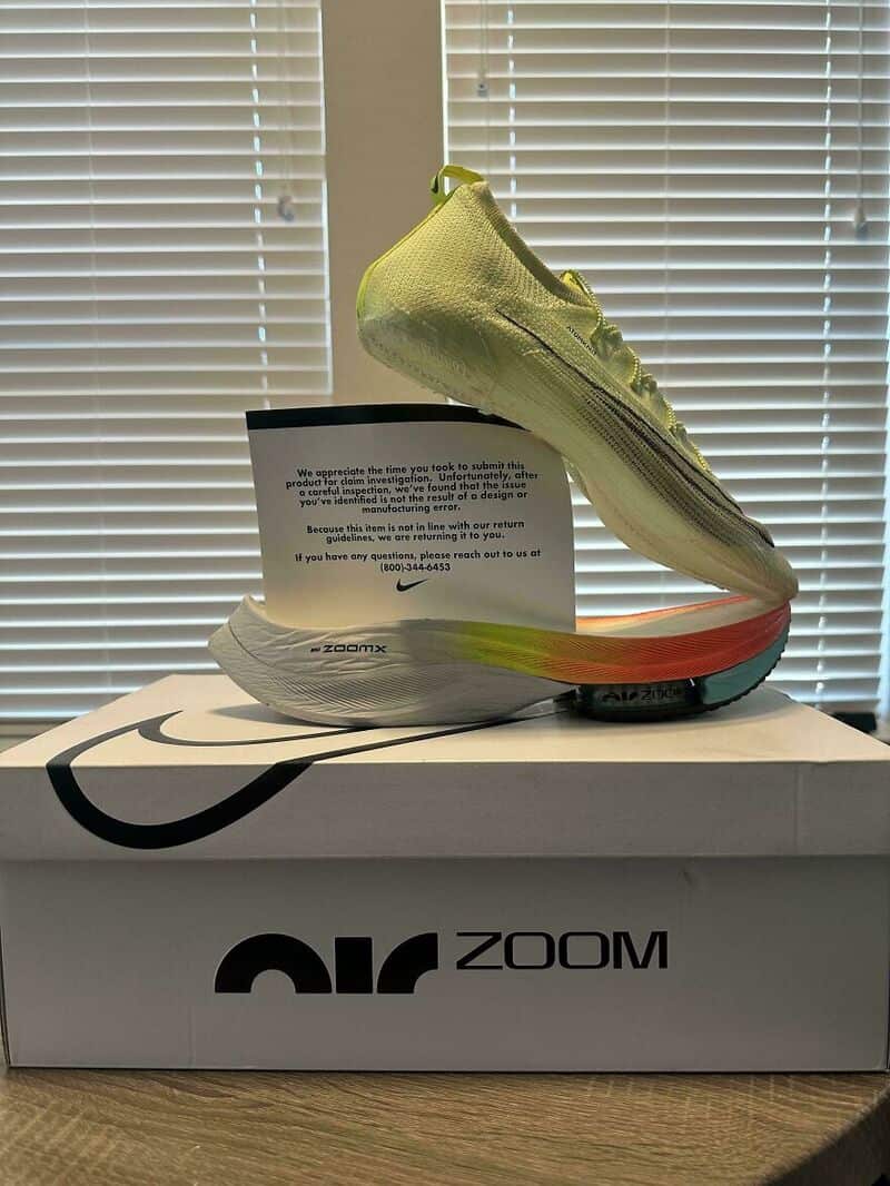 Nike Zoom running shoe displayed on a box with blinds in the background.