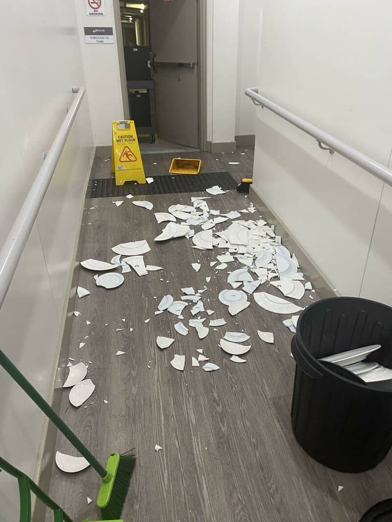 Broken ceiling tiles scattered on the floor in a hallway.